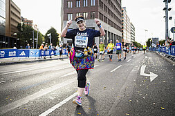 BMW BERLIN-MARATHON 2023: weibliche Läuferin hält die Hände hoch und lächelt in die Kamera © SCC EVENTS / Sebastian Wells